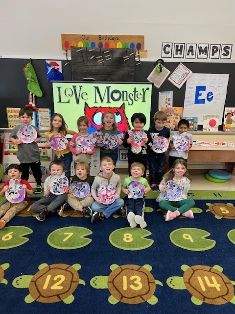students in classroom holding monsters they created 