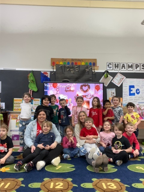 students and teachers sitting on the rug in classroom