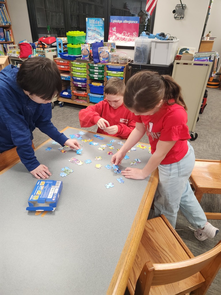 three students working on puzzle on a table