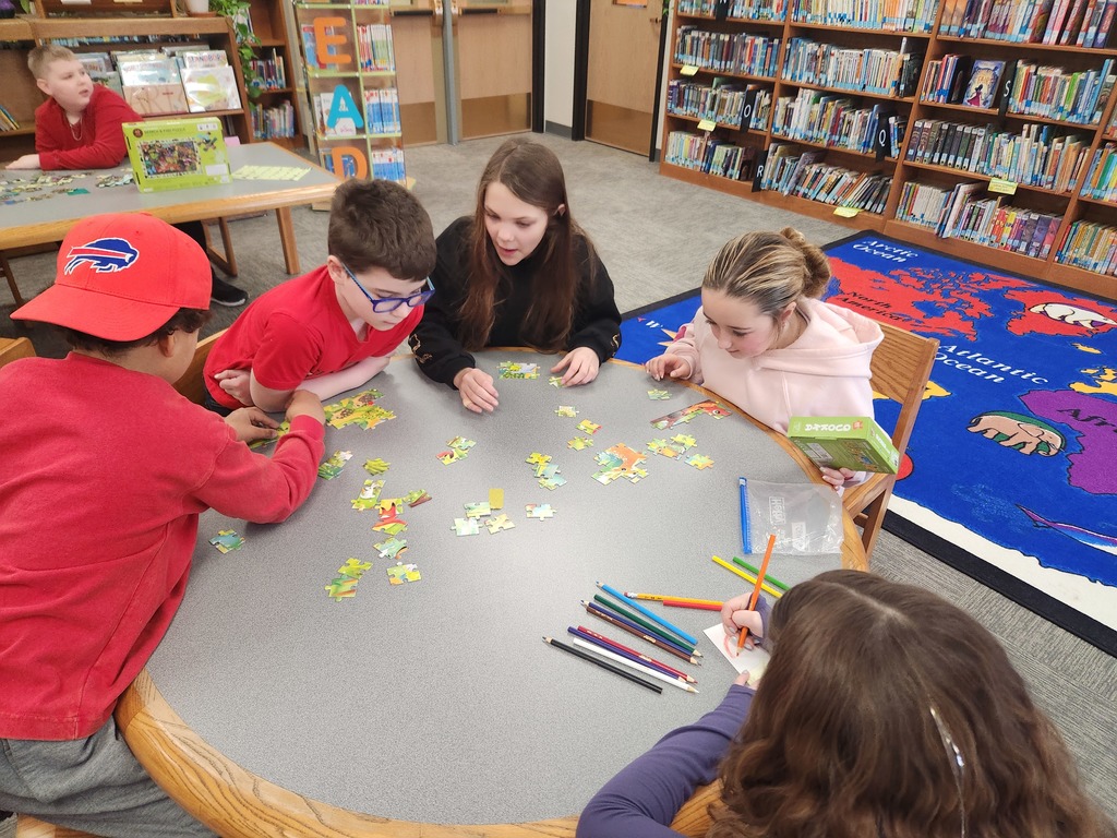 five students working on a puzzle on a table in the library