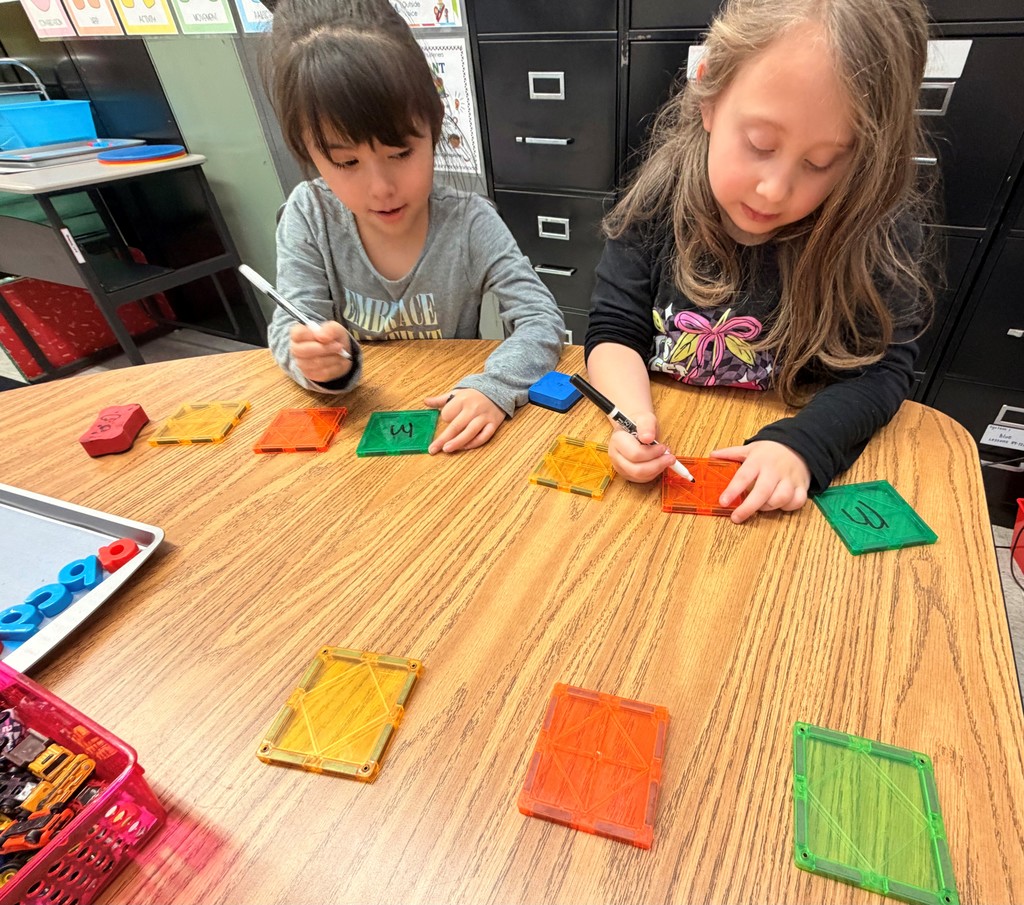 two students writing on colored tiles