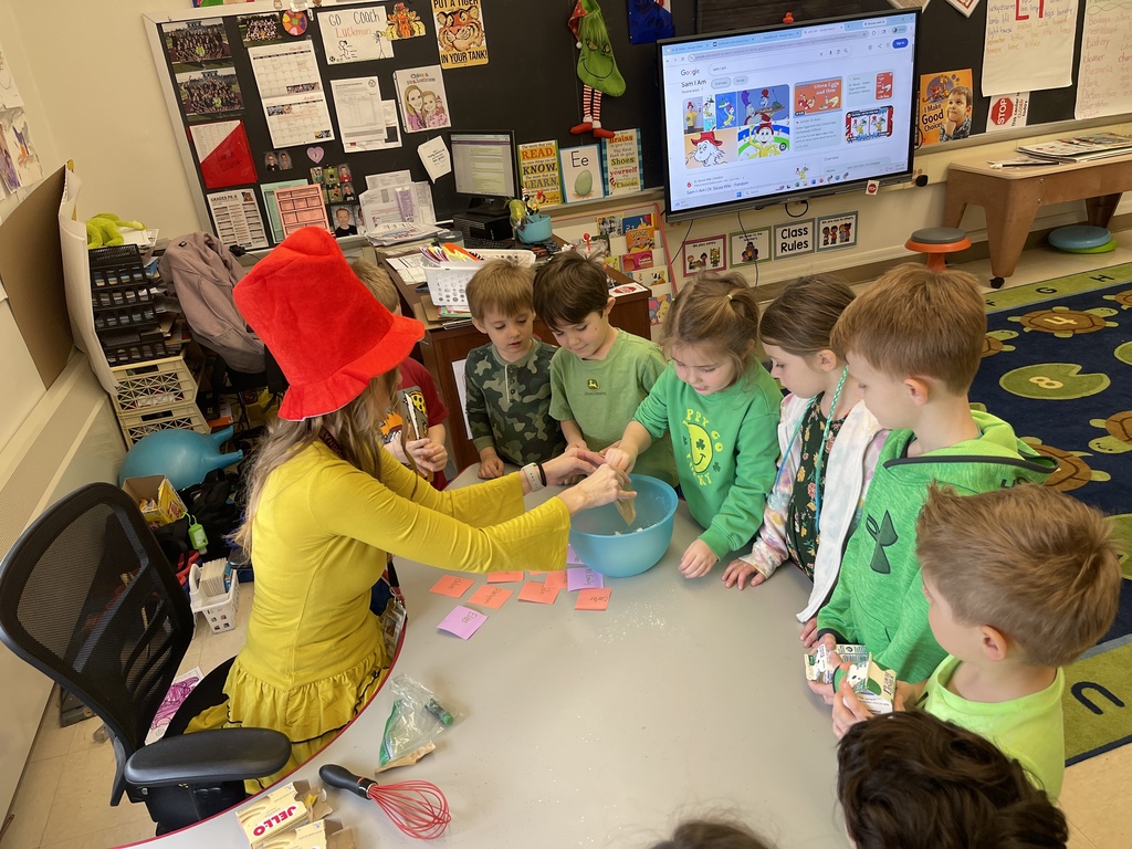teacher and student stirring food in bowl while other students watch