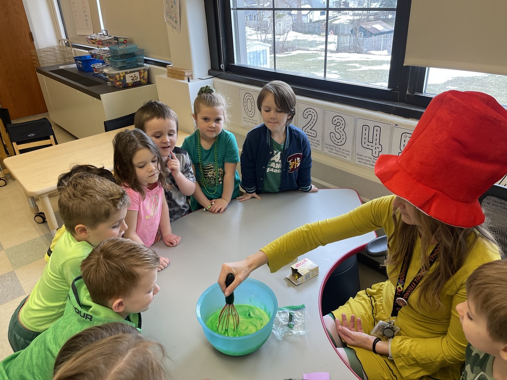 teacher mixing food in bowl while students watch