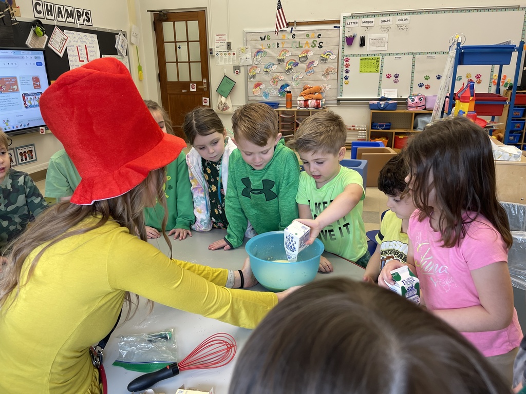 student adding ingredient to bowl while teacher and students watch