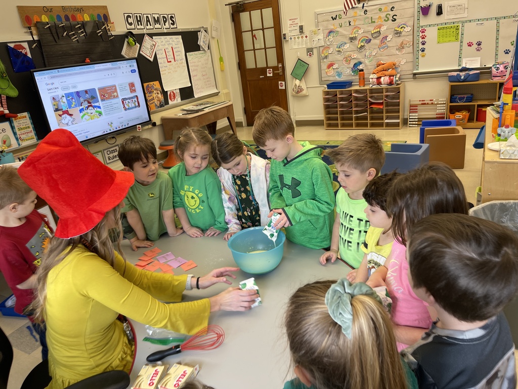 student adding ingredient to bowl while teacher and students watch