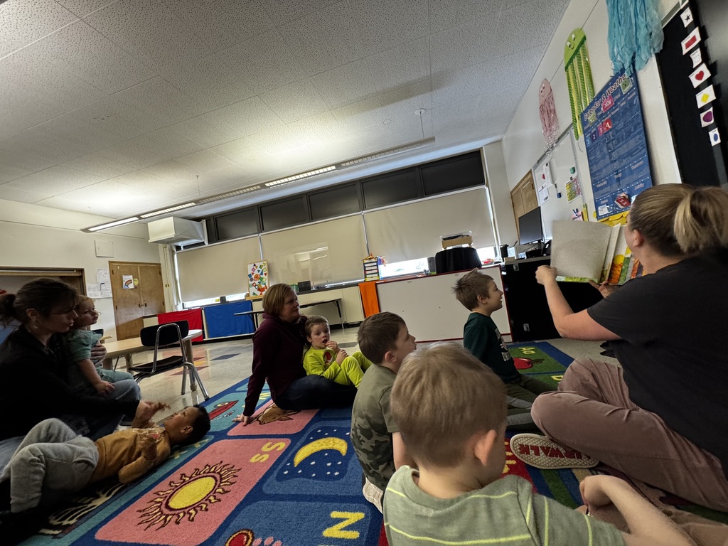 students sitting on rug with teachers listening to a story