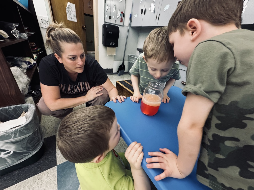 students looking at liquid in a cup with teacher