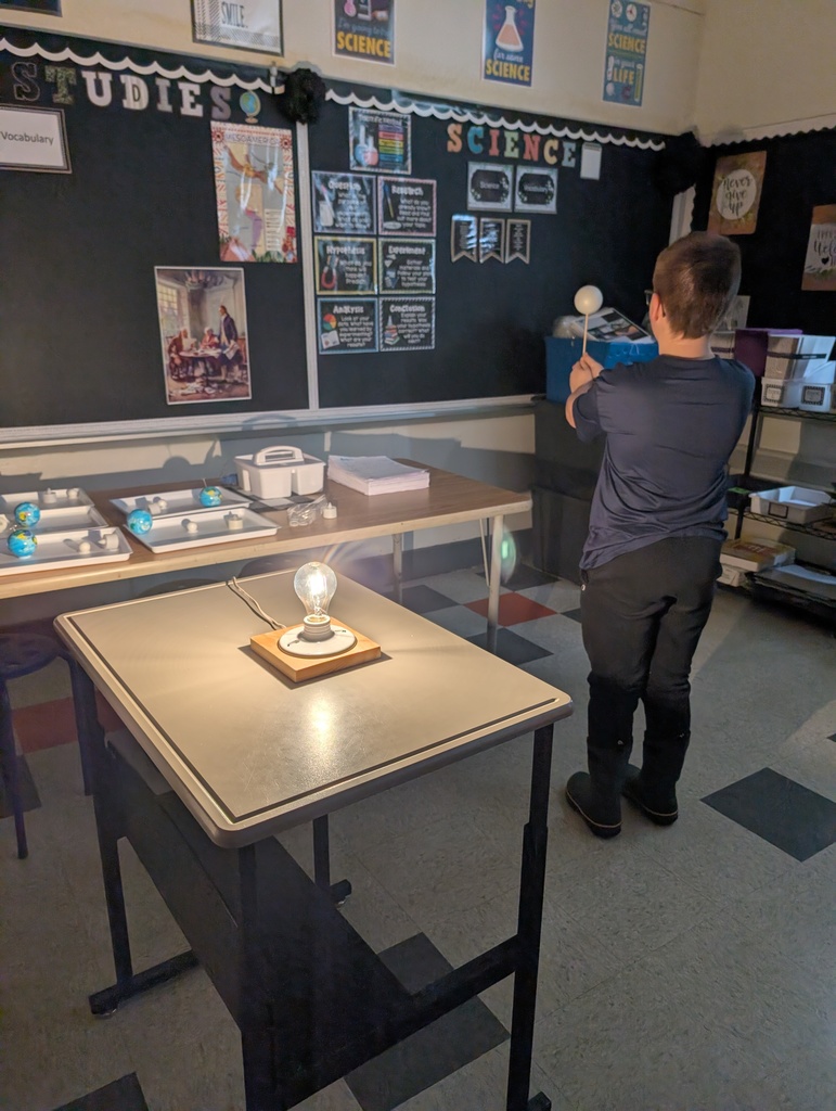 a student holding a ball on a stick with a light behind him