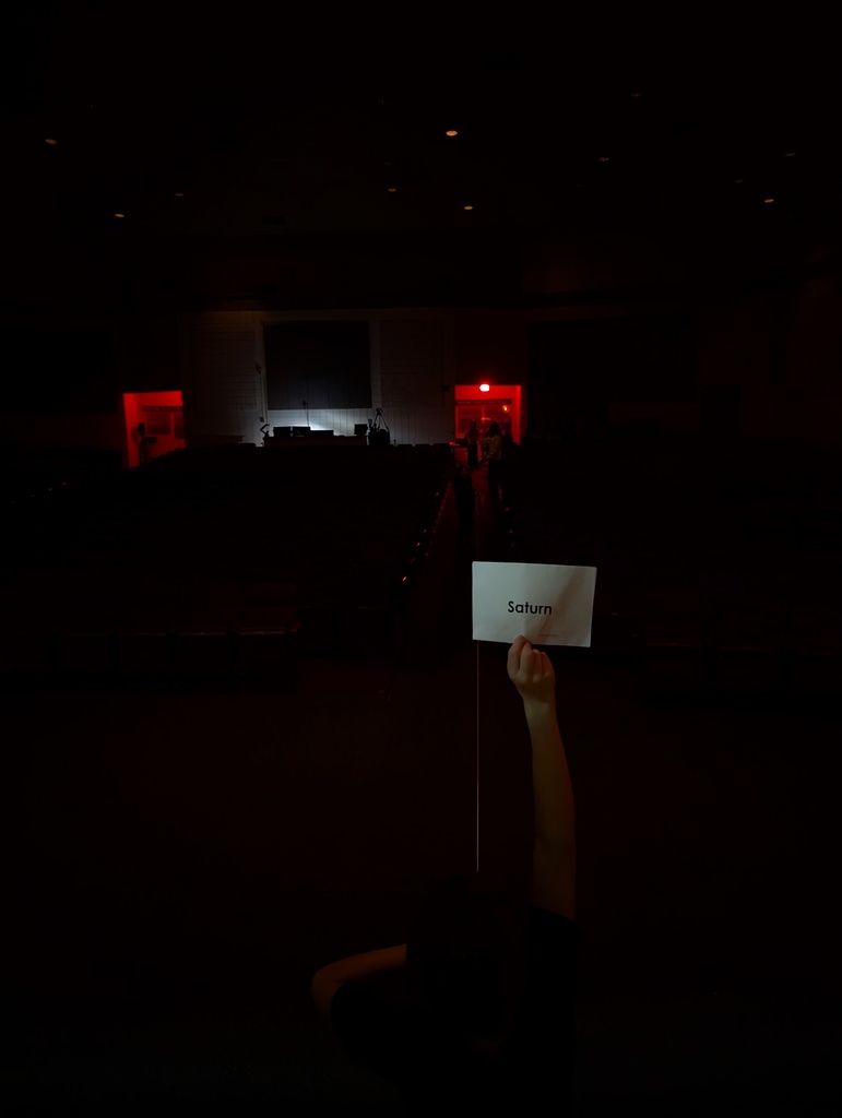 student holding up paper in auditorium