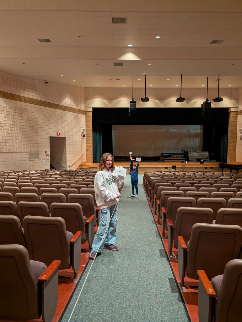 students in auditorium holding up string and paper