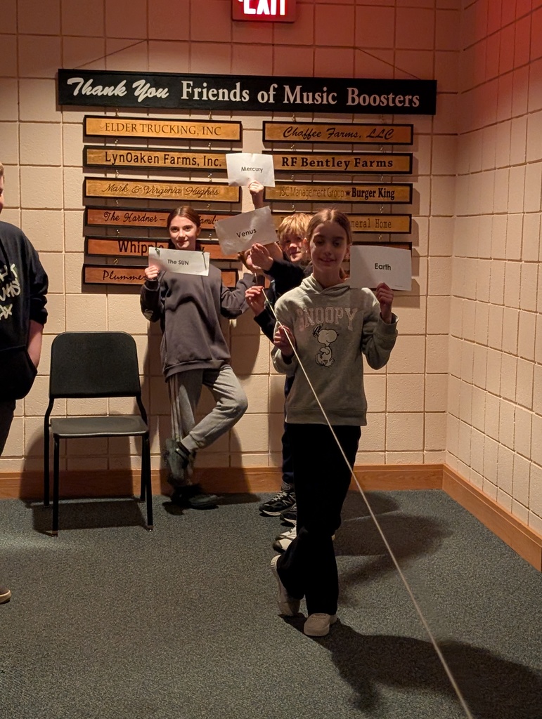 students in auditorium holding up string and paper