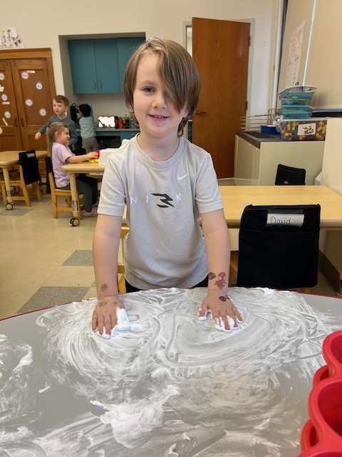 boy playing with shaving cream on table