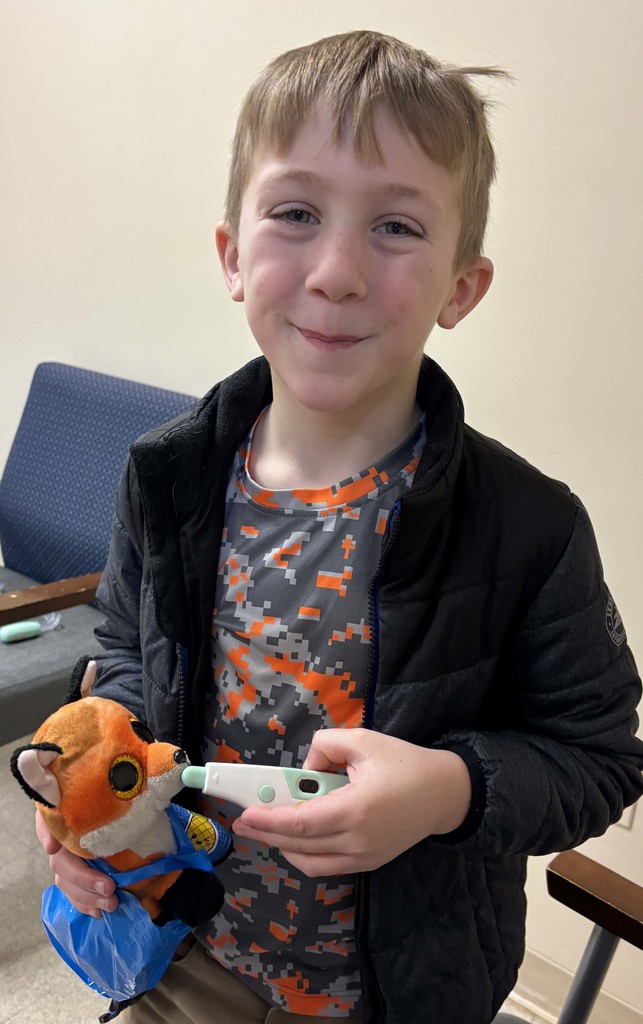 boy holding thermometer in stuffed animal's mouth