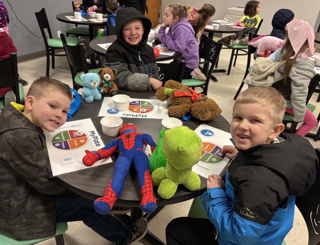 students sitting at tables with their stuffed animals