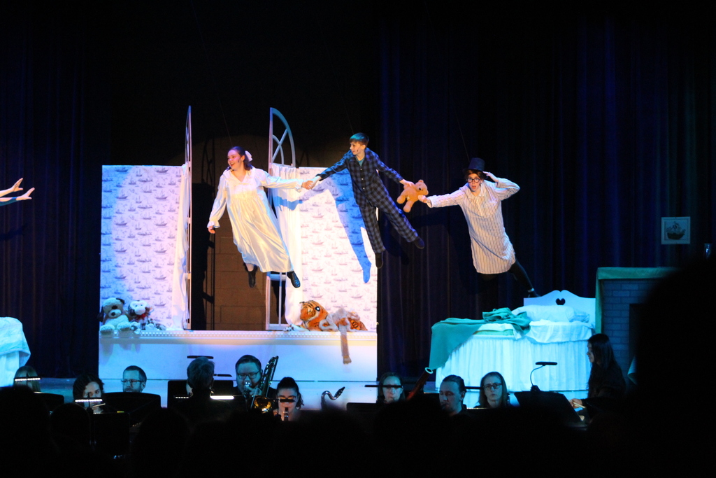 three students flying in air on stage