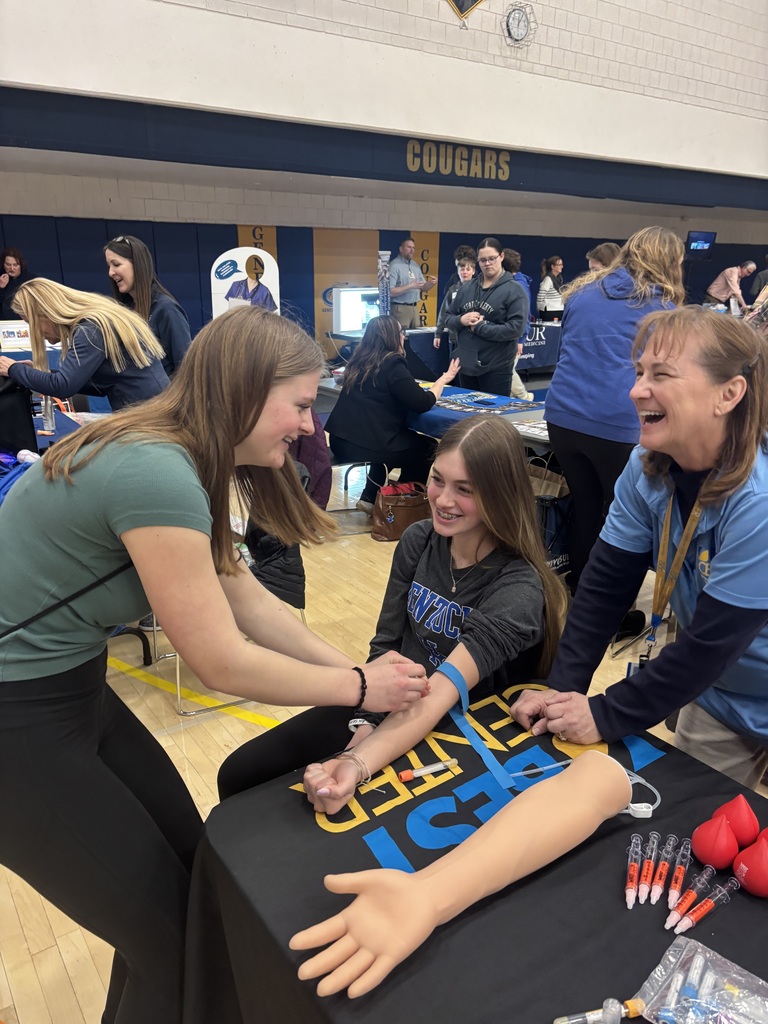 a student taking a blood draw on another student while adult observes