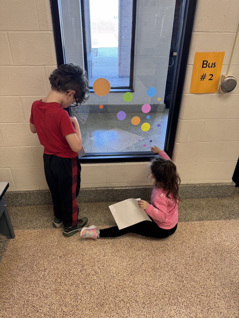 two students adding polka dots clings to window