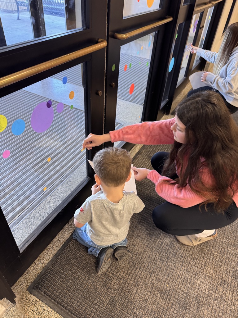 two students adding polka dot clings to windows