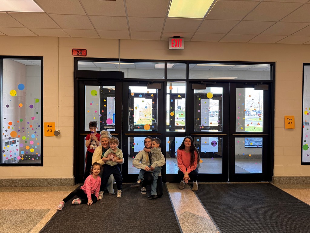 students and teachers in front of windows and doors with polka dot clings on them