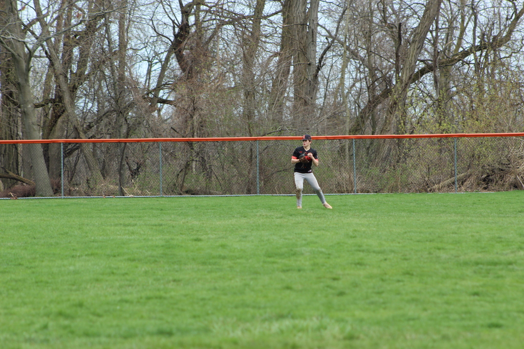 boy throwing baseball in outfield