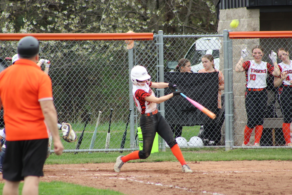 girl hitting ball with bat in softball game