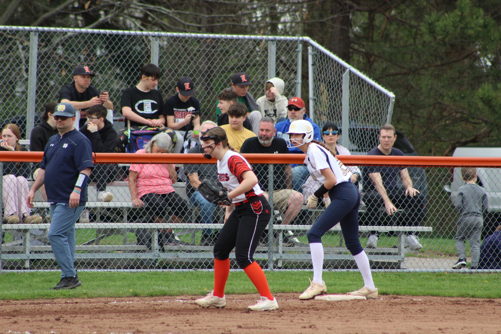 girl guarding third base while another girl is on base in softball game
