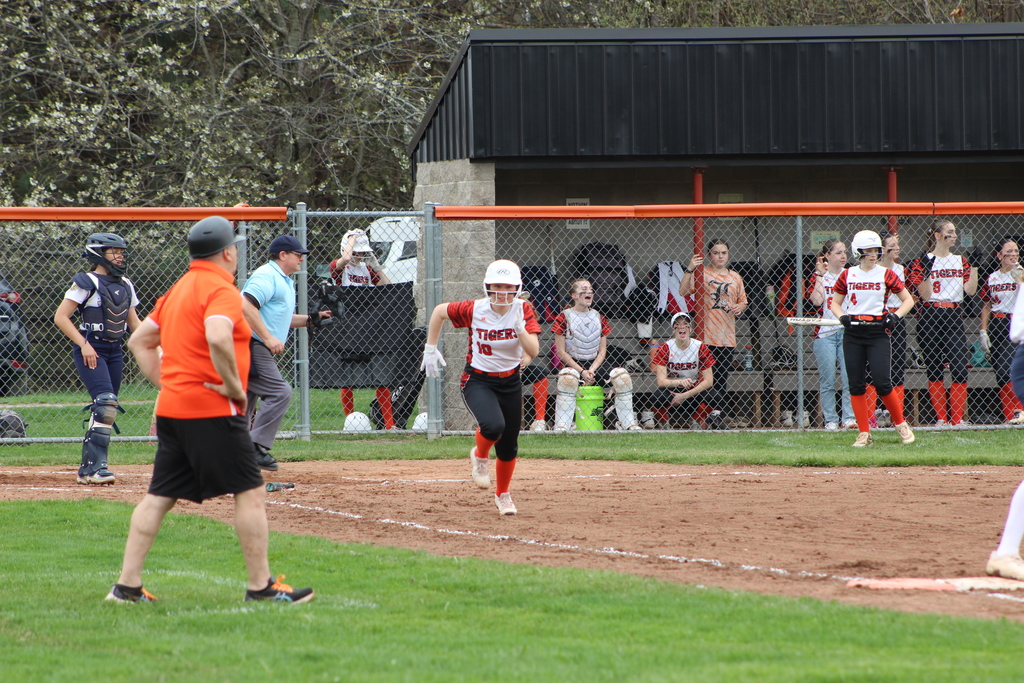 girl running towards first base in softball game