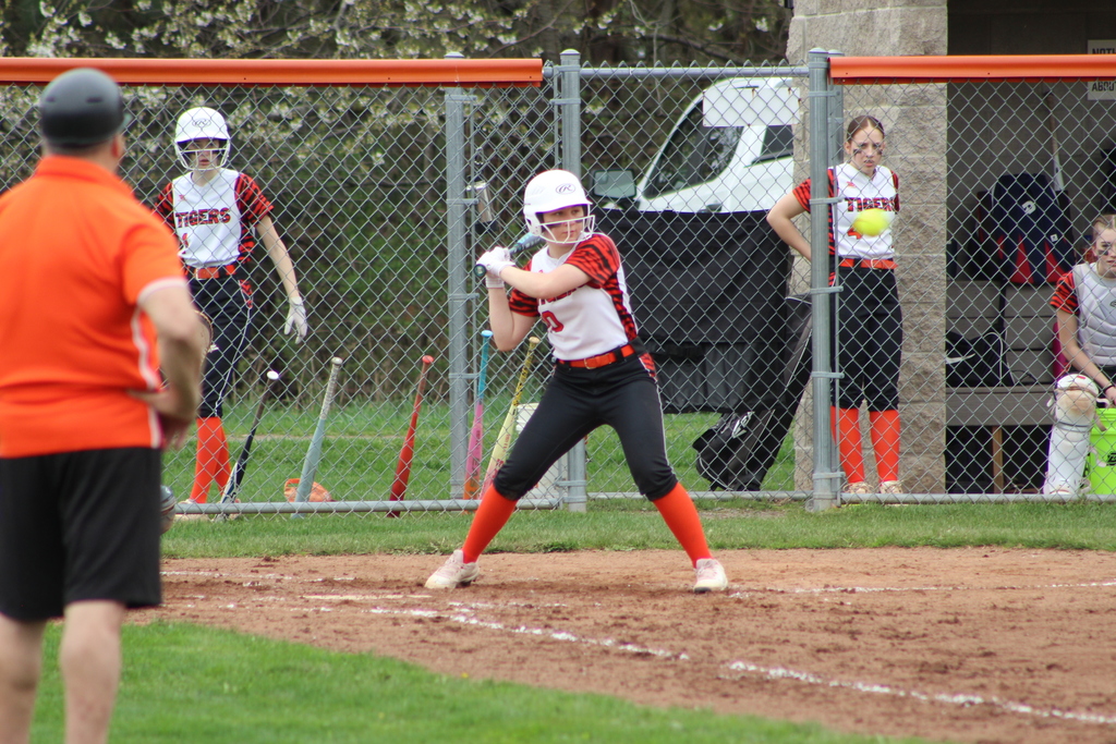 girl hitting ball with bat in softball game
