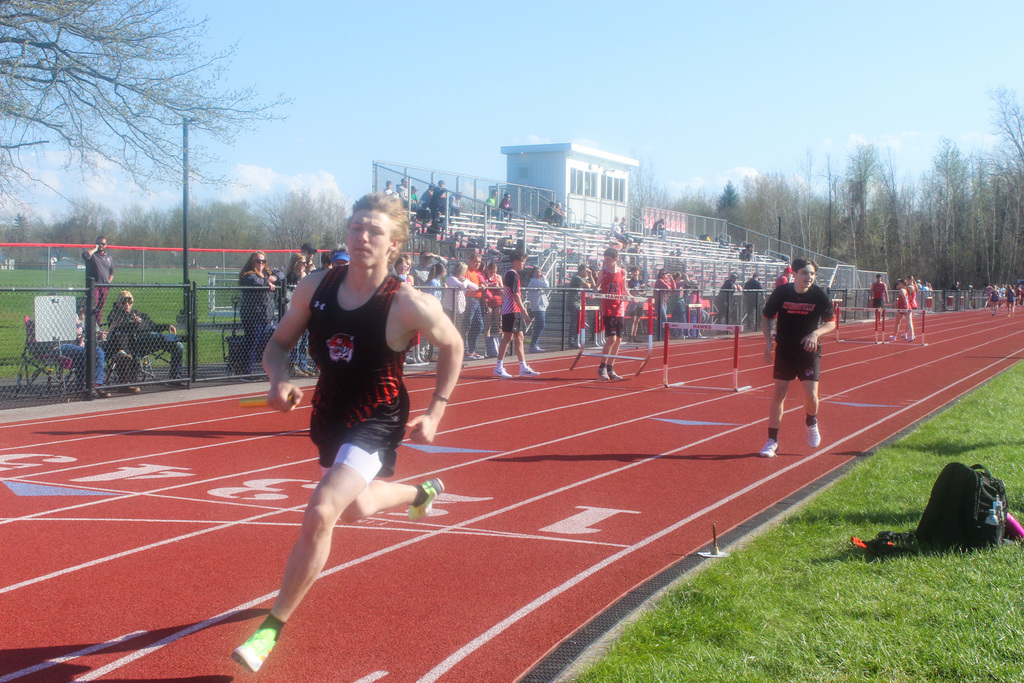 boy running relay with baton on track