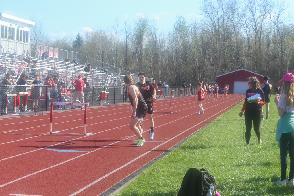 two boys handing off baton in relay race on track