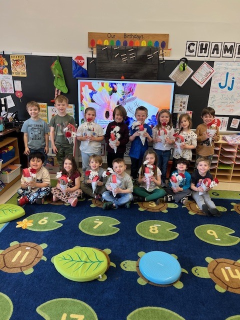 students holding flowers they made in classroom