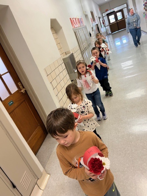 students walking down the hall holding flowers they made