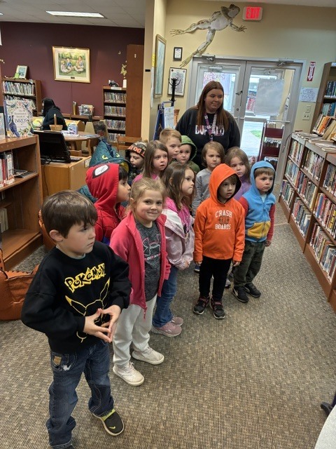students standing in a row in the library with adult