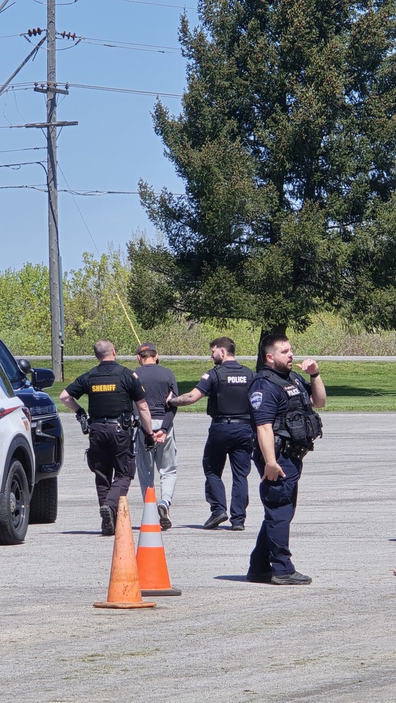 a student being lead to patrol car by law enforcement officers