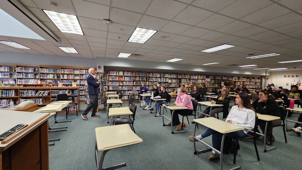 students listening to adult speak in library