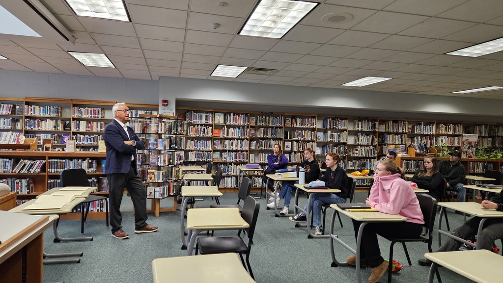 students listening to adult speak in library
