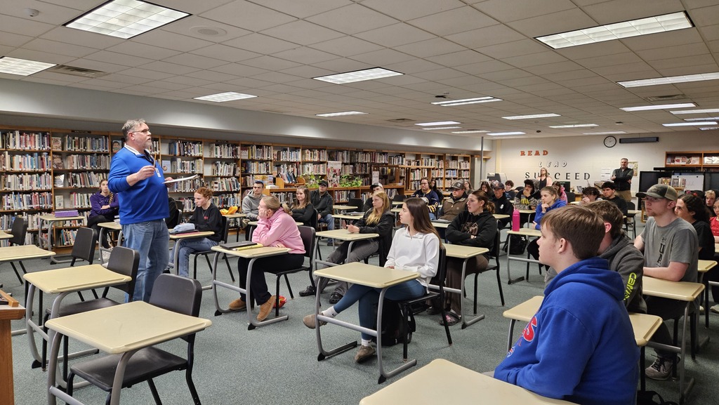 students listening to adult speak in library