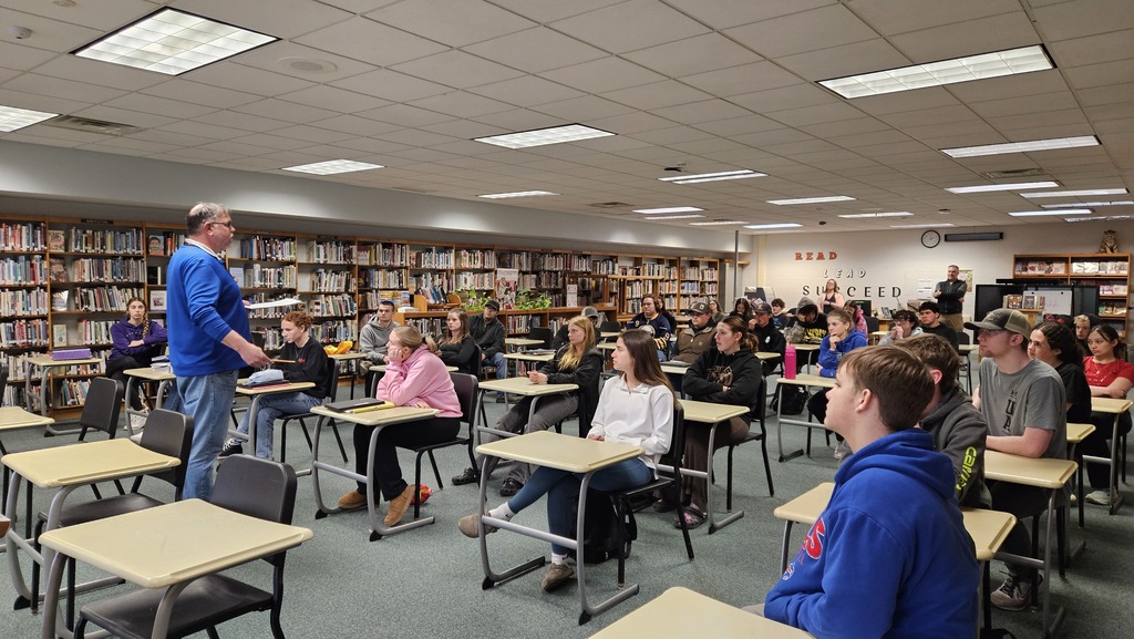 students listening to adult speak in library