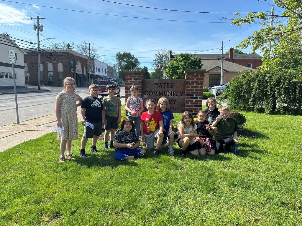 students grouped on lawn in front of public library sign