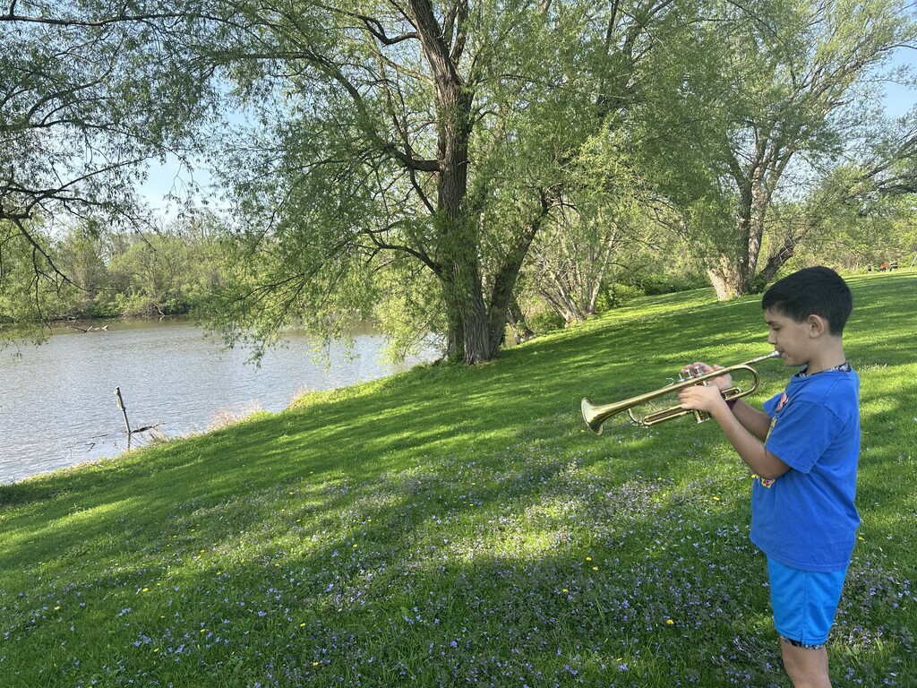 student playing trumpet outside near river