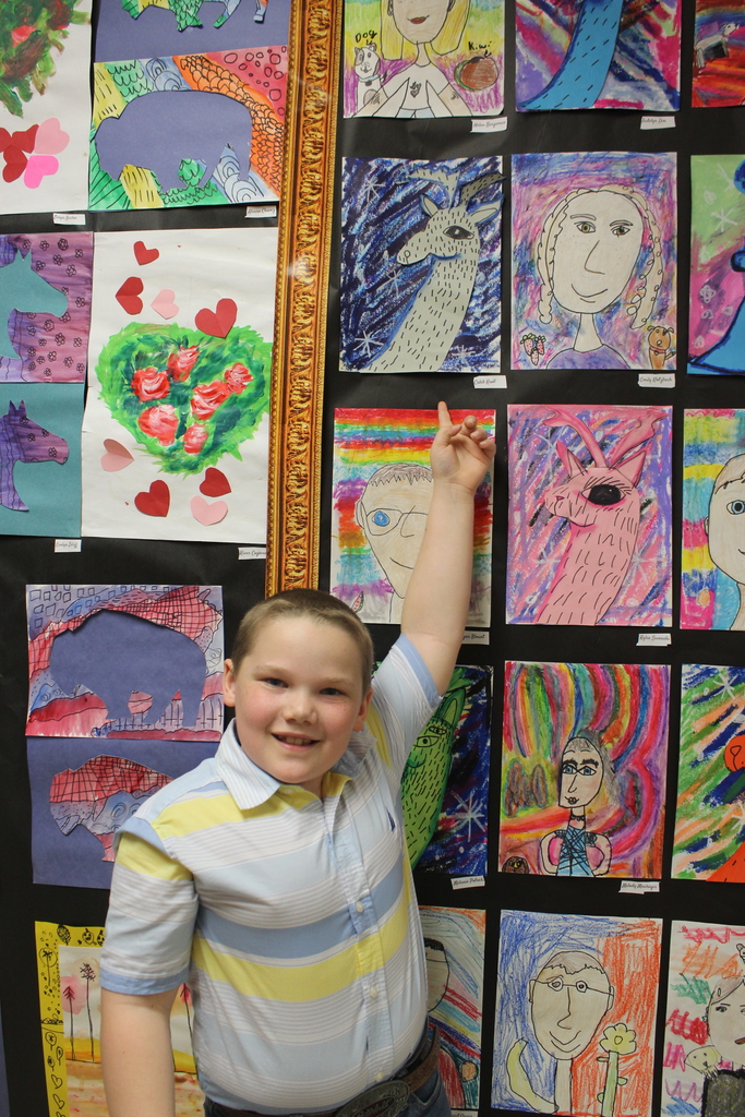 boy pointing to his artwork hanging on the wall