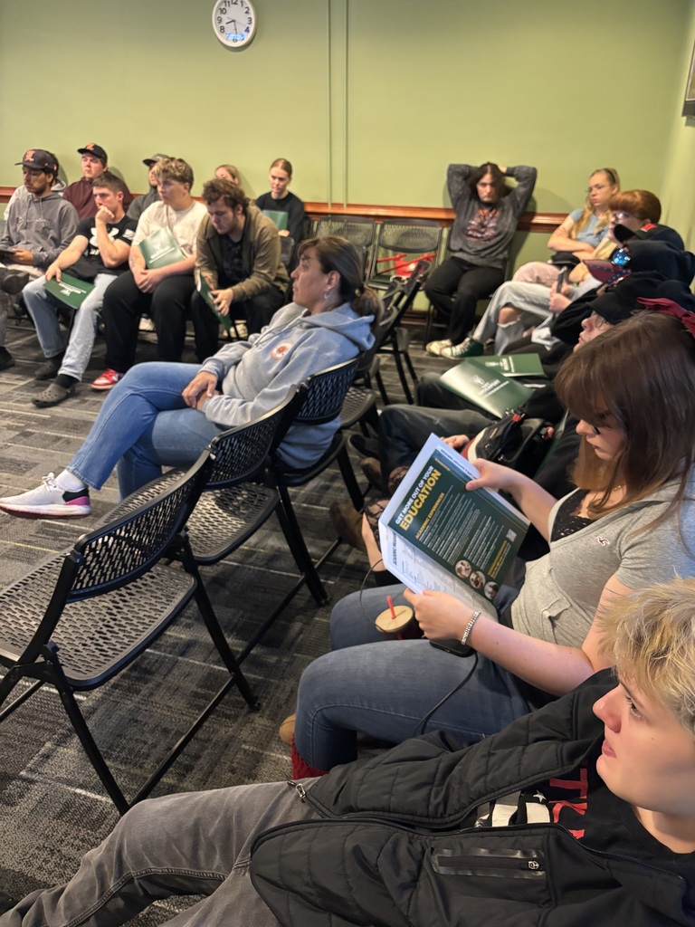 students and staff seated in a room listening to a speker