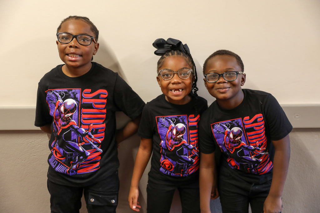 three students posing with spiderman shirts