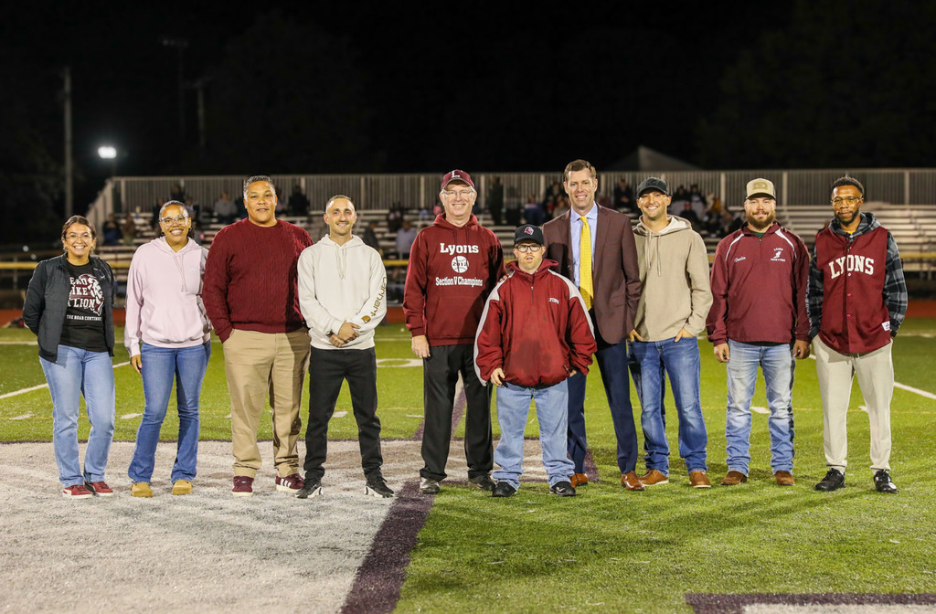 group of athletic hall of fame inductees on the football field being recognized