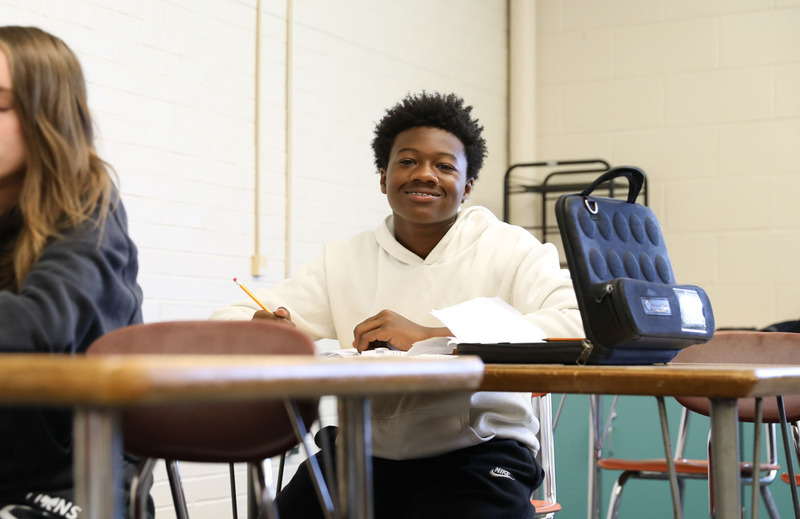 student at desk writing and smiling