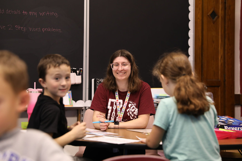 teacher at desk helping students with math