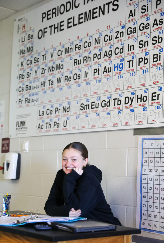 student in front of the periodic table poster