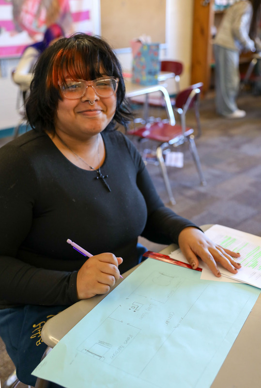 student smiling while she works on blueprint