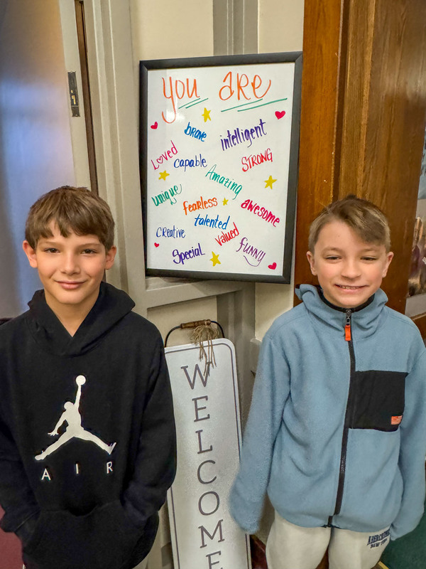 students posing in front of door board