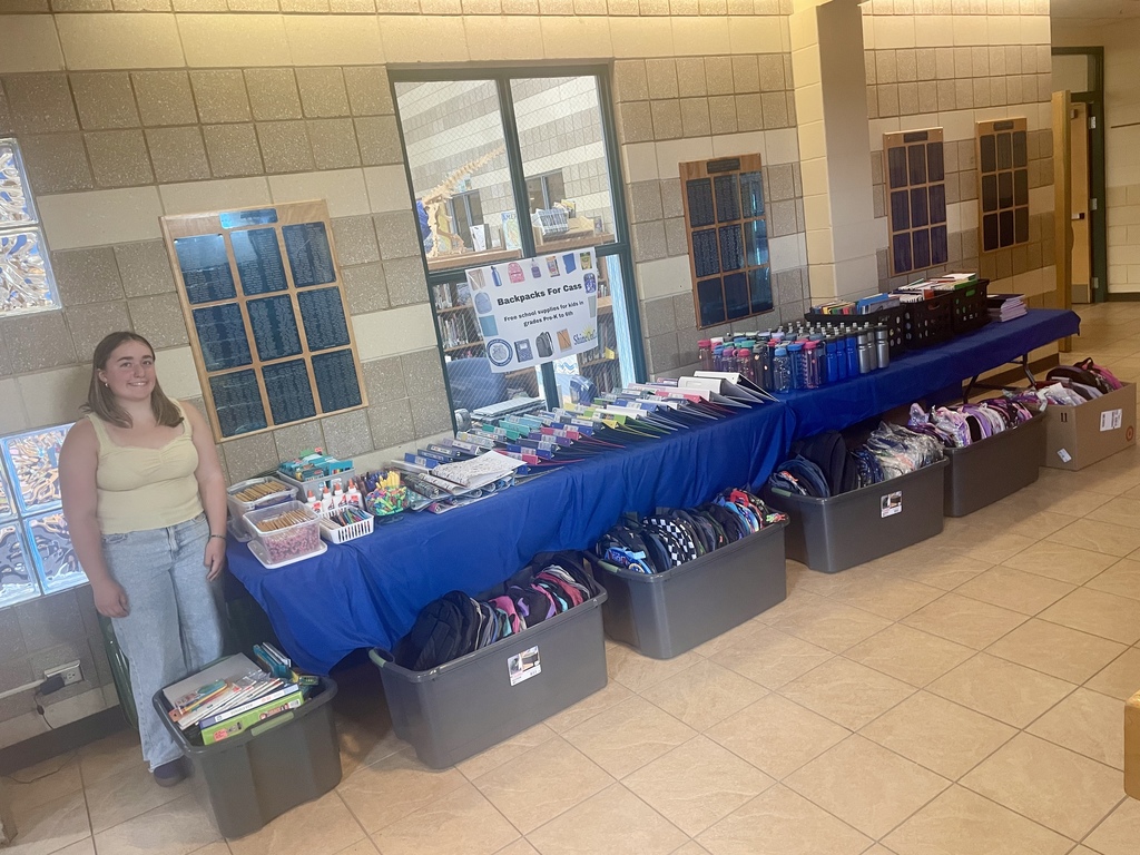 A table full of school supplies and back packs to be given to students.